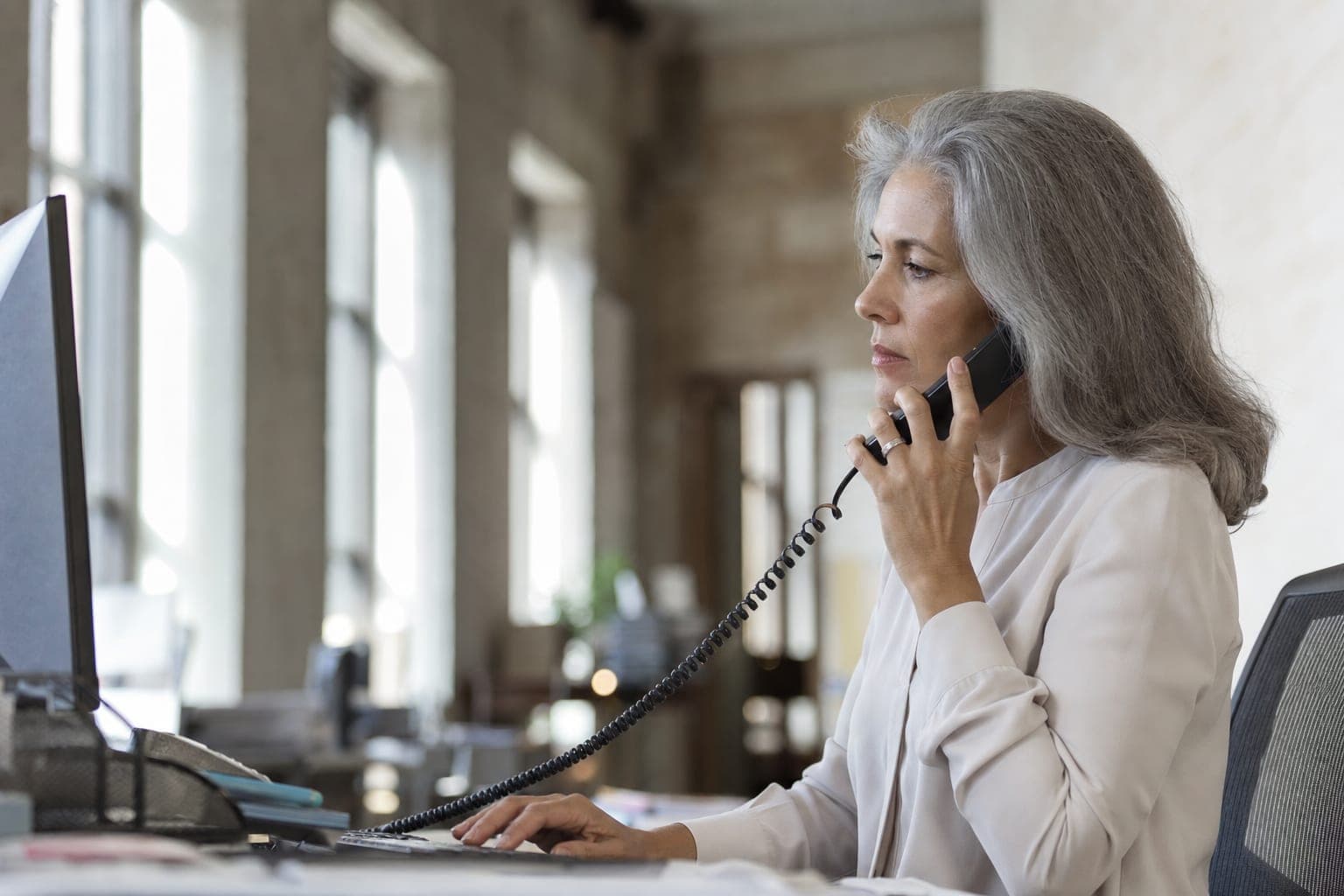Mitarbeiterin im Telefonat am Schreibtisch, bereit für Ihr Erstgespräch